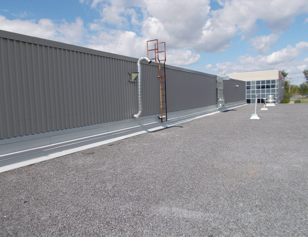 Le rebord d'un toit plat industriel refait, parapet de métal gris, ciel couvert