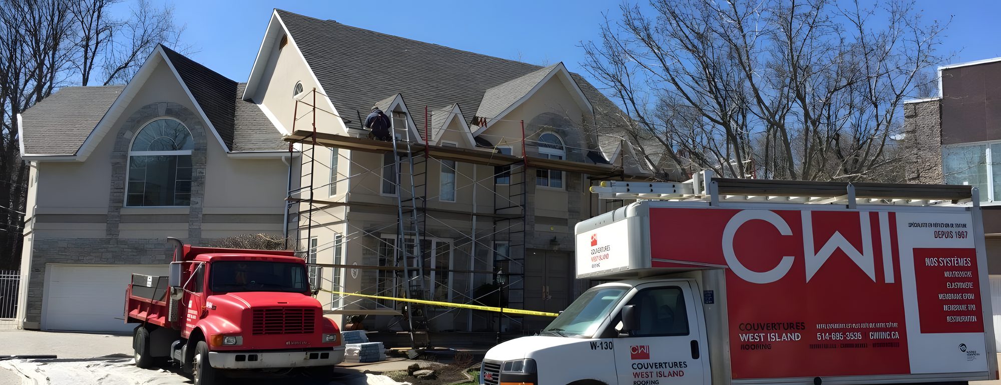 Une maison de brique en réfection de toiture : échafaud contre la façade, camion rouge et fourgon blanc de CWI dans l'entrée
