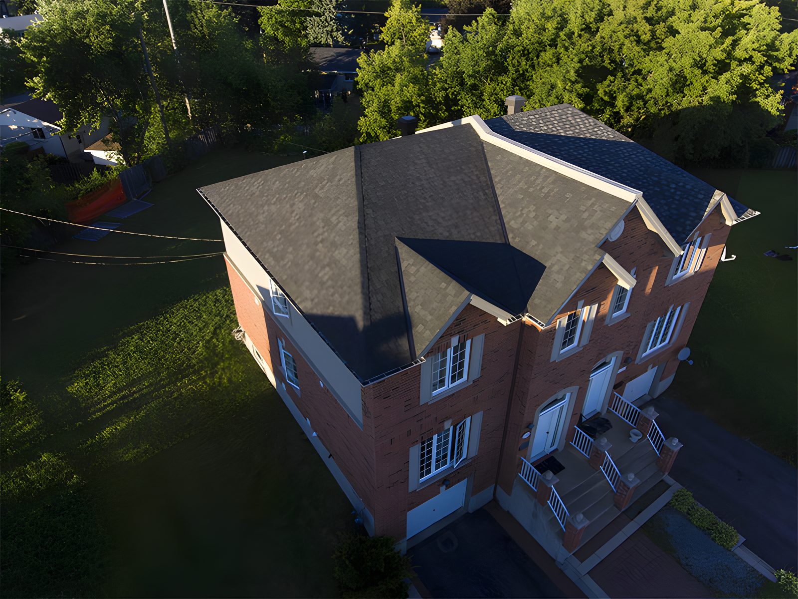 Vue drone d'une maison de brique rouge au toit de bardeau gris, entrée pavée